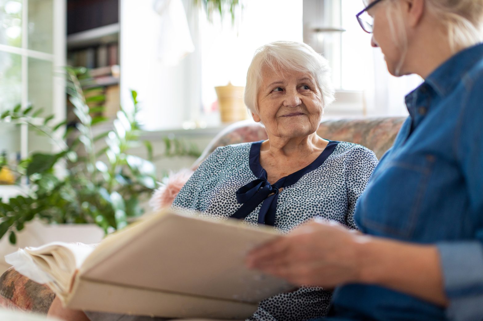 A memory care staff member reads to an older resident