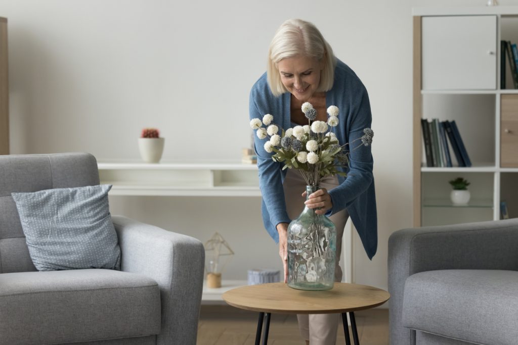 A woman decorates her maintenance-free independent living apartment with cozy furnishings