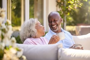 Retired Couple Sitting Outdoors At a Senior Living Community Having Morning Coffee Together