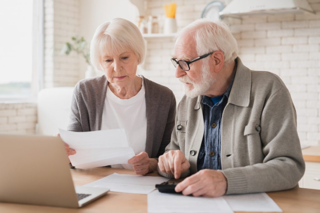 A senior couple going over their finances together to determine if they can save money by moving into an independent living community.