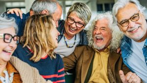 A group of newly retired people huddles together, laughing, and enjoying each other's company.