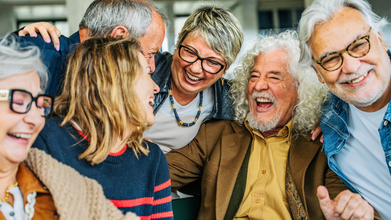 A group of newly retired people huddles together, laughing, and enjoying each other's company.