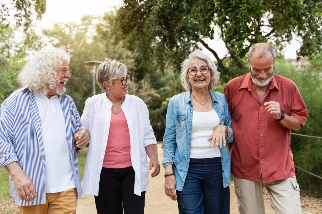 A group of senior friends walking outside in an independent living community.