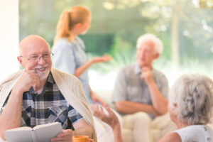 Senior Man with Book Talking to Woman at Table_Community Senior Life