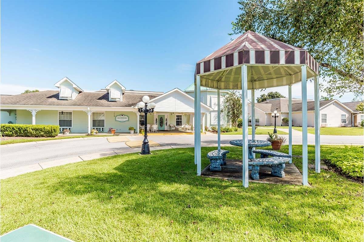 The outside of Homestead Village features a gazebo and a lush, green lawn.